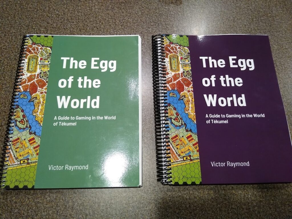 two books on a flat surface, on the left is green with colorful graphic, title The Egg of the World, on the right purgple with colorful graphic and title: the Egg of the World.